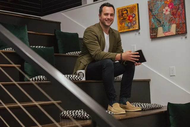 Autónomo sonriente sentado en una escalera con una tableta en la mano